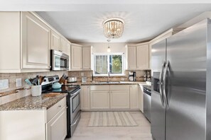 Una cocina moderna con electrodomésticos de acero inoxidable, armarios de tonos claros y un amplio ventanal que proporciona luz natural.