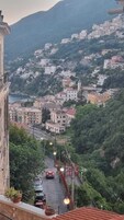Uma vila situada numa encosta, com edifícios, uma estrada e um corpo de água ao longe.