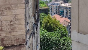Un balcón con vistas a un pueblo costero, edificios y un paisaje montañoso.