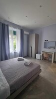 Quarto moderno com uma cama grande, uma escrivaninha, um guarda-roupa e uma janela com cortinas.