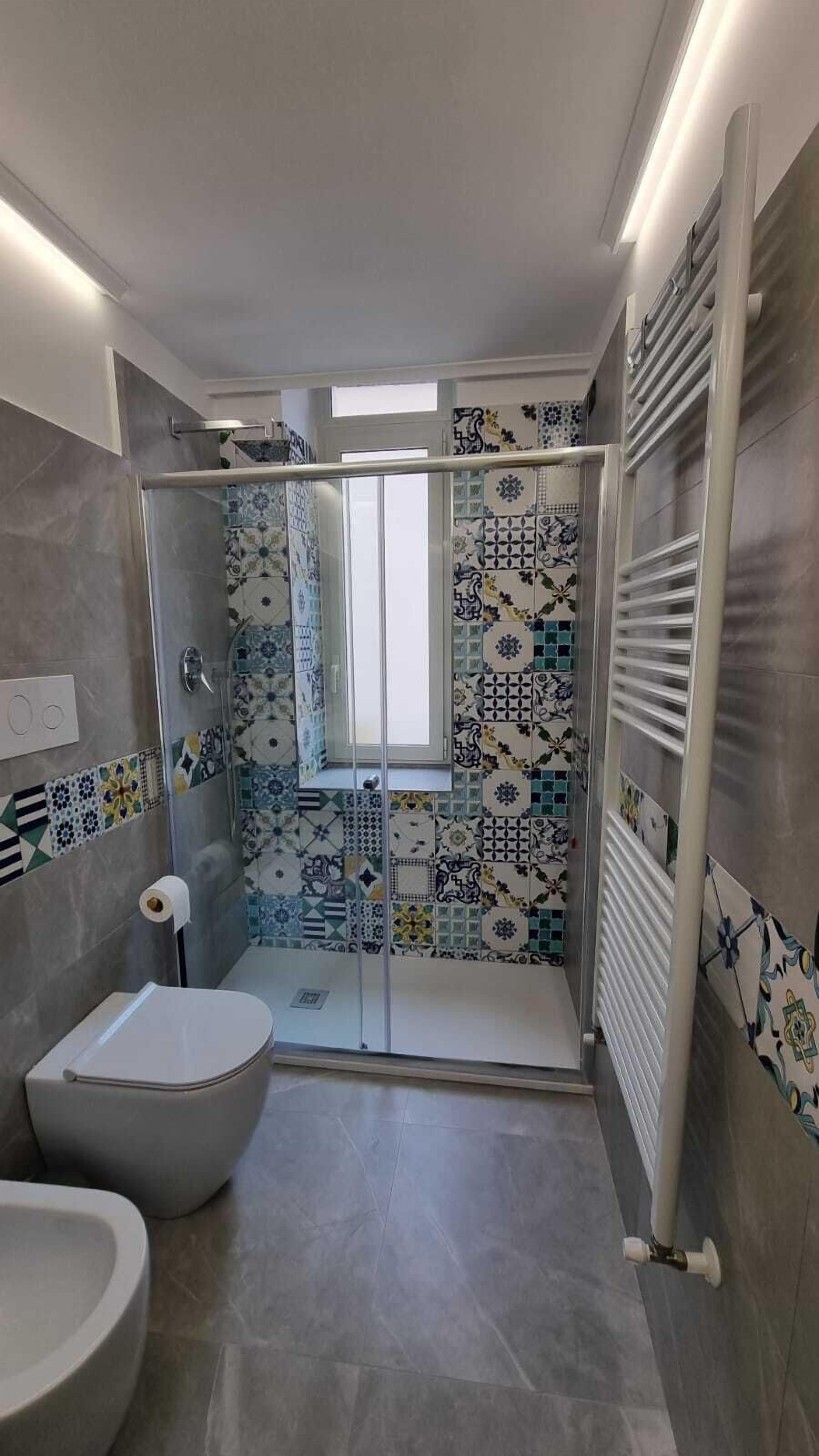 A modern bathroom with a glass shower enclosure, a toilet, and a sink.