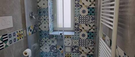 A modern bathroom with a glass shower enclosure, a toilet, and a sink.