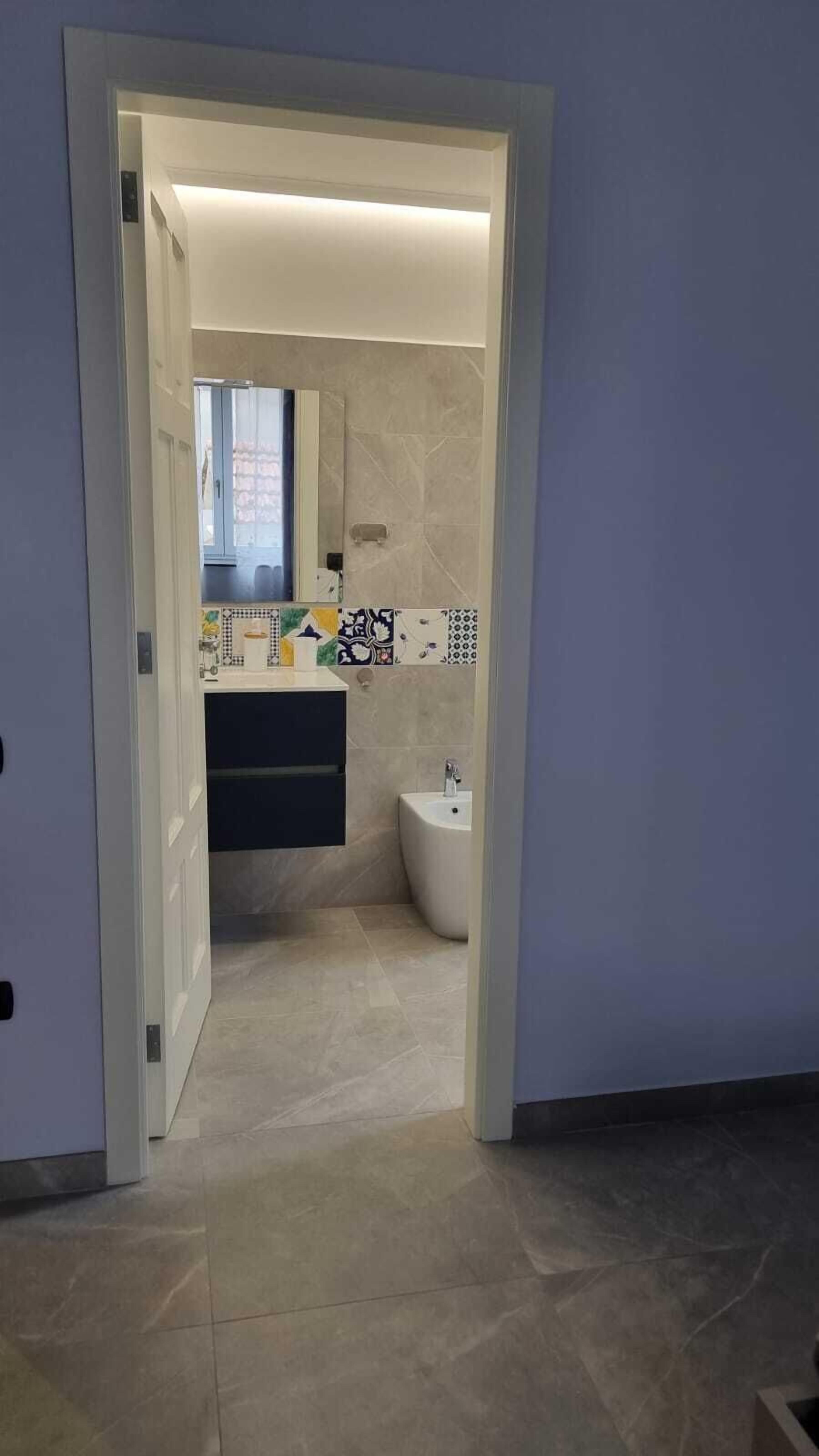 Une salle de bain moderne avec un carrelage au sol, un lavabo et des toilettes.