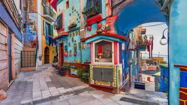 Una calle estrecha con edificios coloridos, una tienda pequeña y un arco azul.