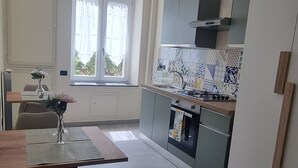 Una cocina moderna con gabinetes grises, protector contra salpicaduras de azulejos y una ventana con cortinas.