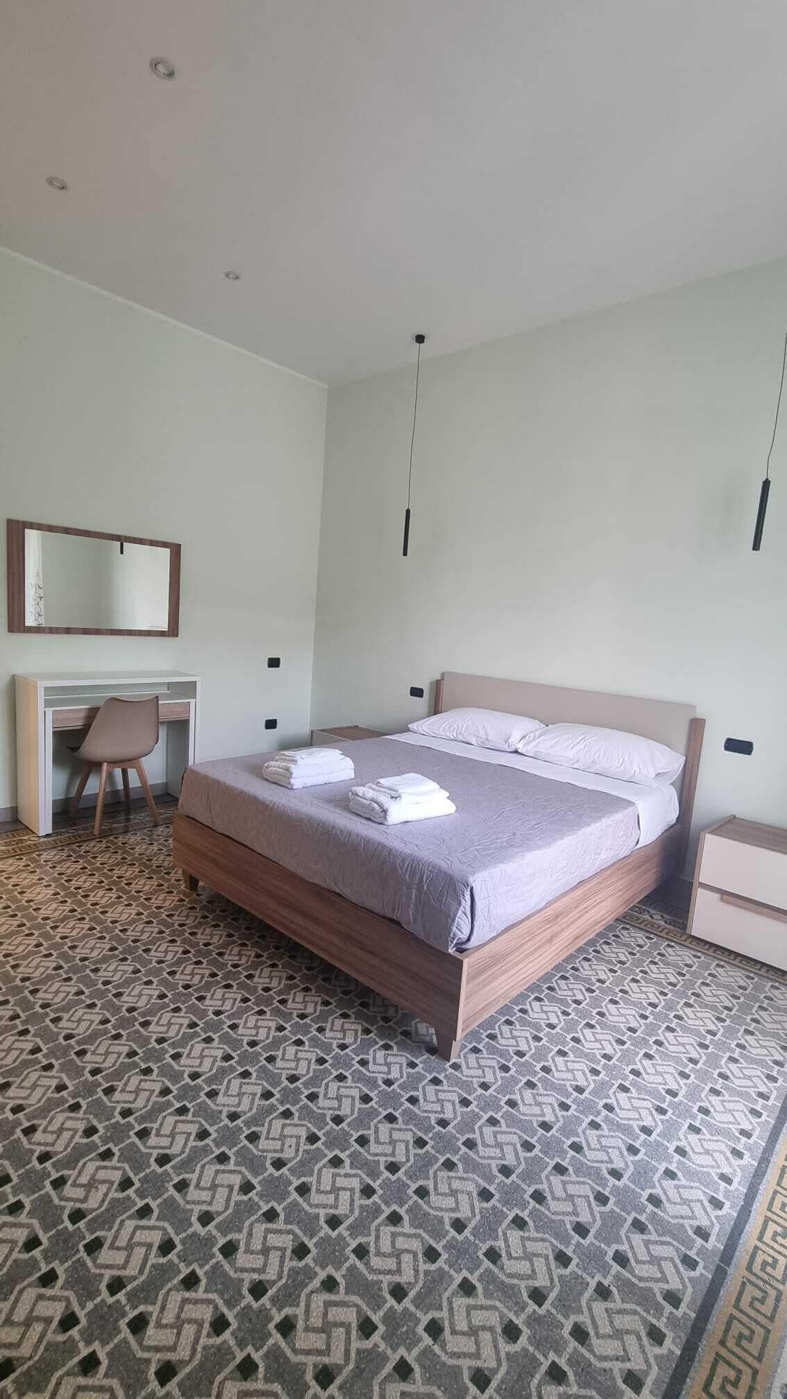 A hotel room with a bed, a desk, and a chair.
