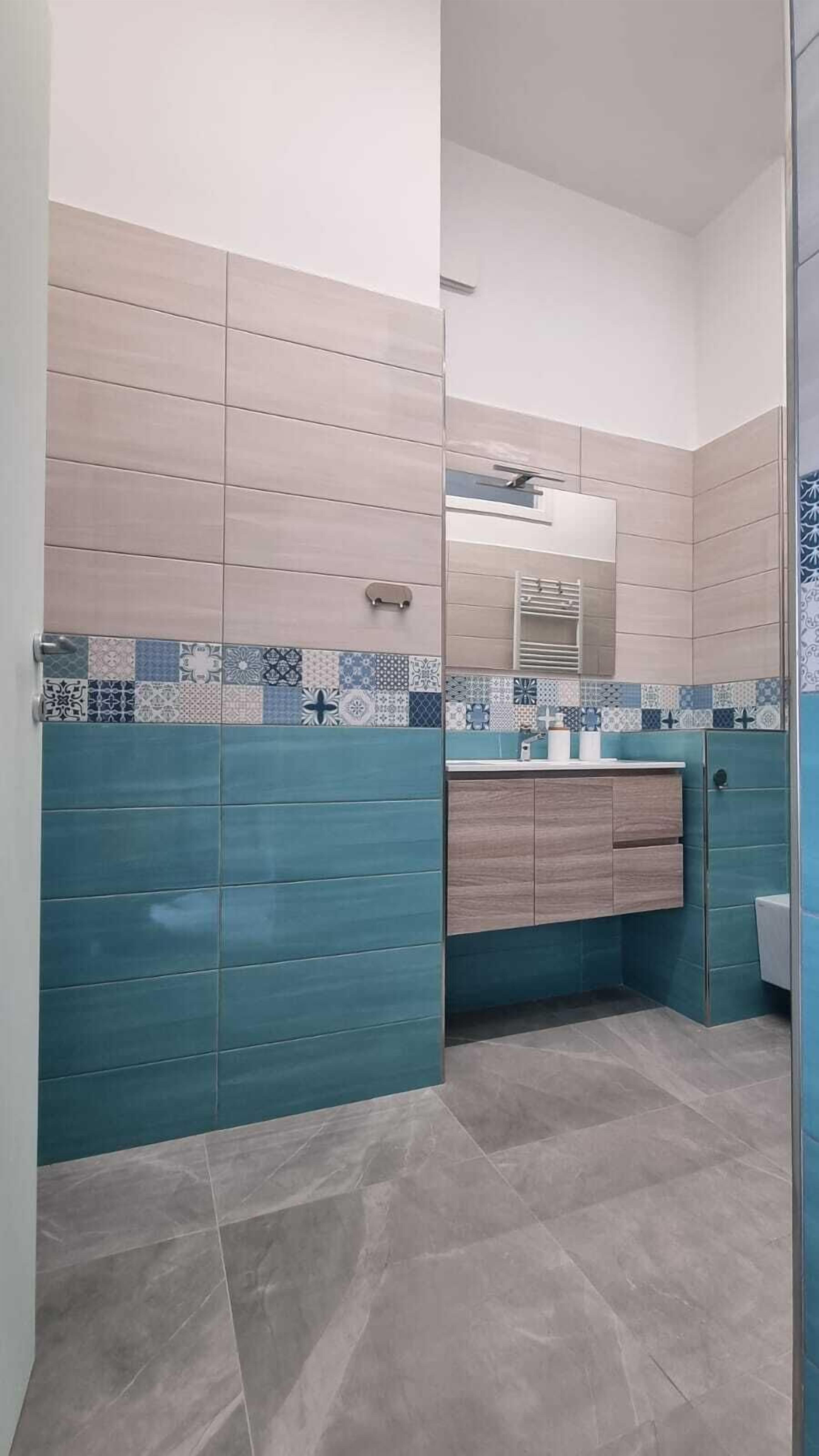 Un baño con salpicadero de azulejos, un espejo, un lavabo y un inodoro.