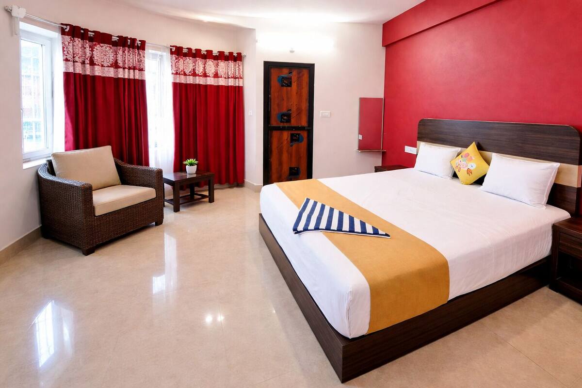 Une chambre d’hôtel avec un lit, un canapé, une petite table avec une plante et une porte.