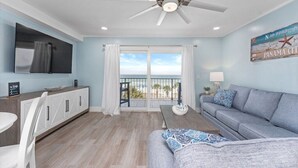 A living room with a grey sofa, a white dining table, and a ceiling fan. - Summit Gulf Front Unit 421 | 4th Floor (Panama City Beach)