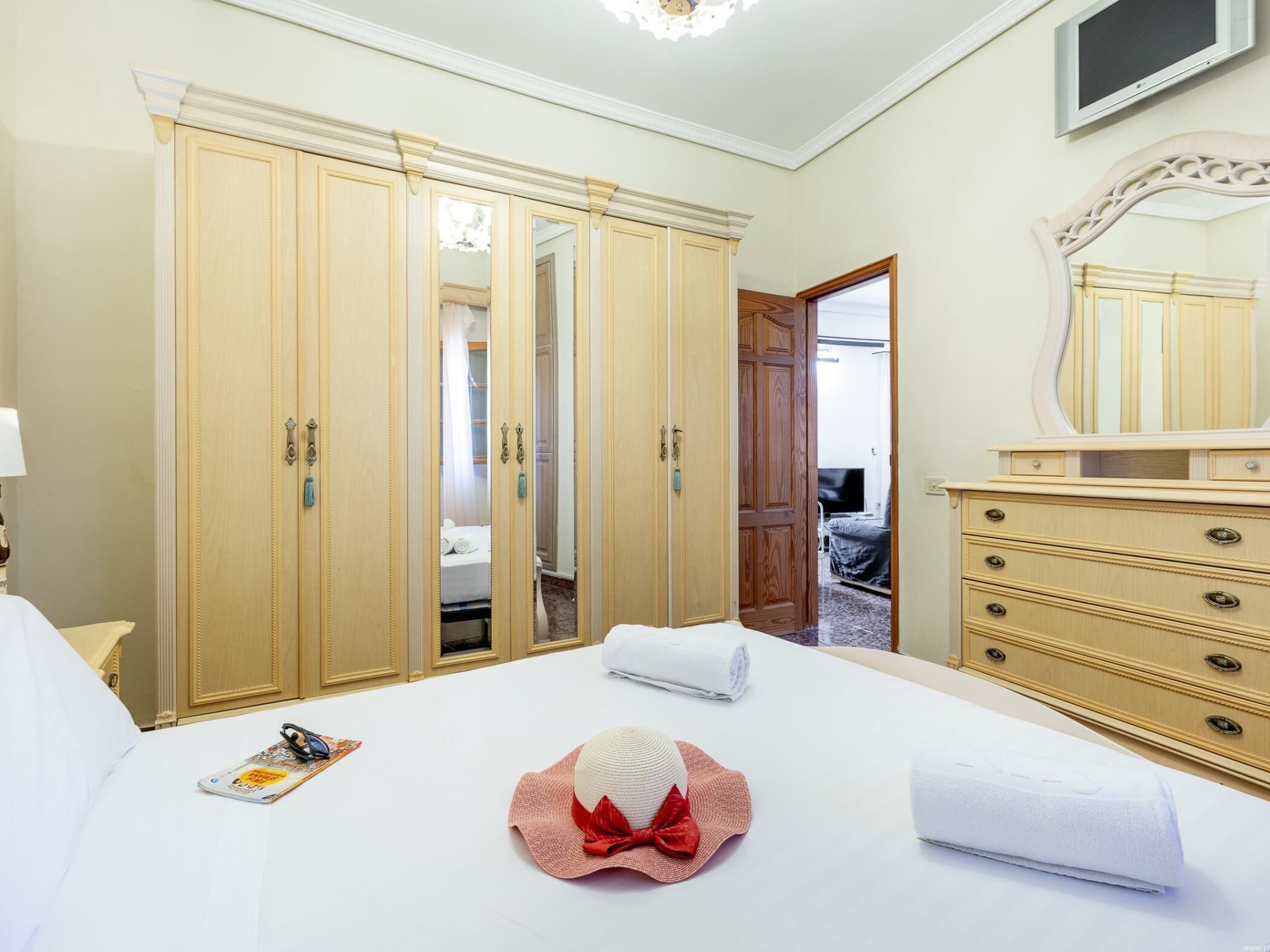 A hotel room with a large bed, a wardrobe, a dresser, and a mirror.