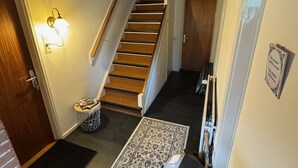 A hallway with a carpeted staircase, a rug, a small table with items, and a wall-mounted light fixture. - B&B Zwiep (Lochem)