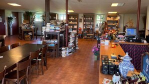 A library with bookshelves, a wooden table, chairs, a computer, and decorative items. - B&B Zwiep (Lochem)