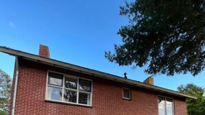 A two-story brick house with a front porch, a small table, and two chairs. - B&B Zwiep (Lochem)
