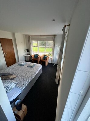 A small, tidy room with a single bed, a chair, a small table, and a window offering a view of the outdoors. - B&B Zwiep (Lochem)