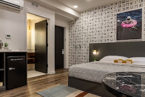 Un dormitorio moderno con cama, un escritorio pequeño, un refrigerador y una pared con un patrón de círculos.