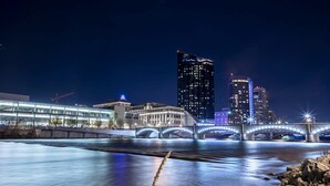 Une vue nocturne d’une ville, avec une rivière, un pont et des bâtiments illuminés.