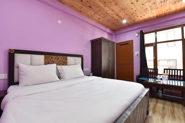A bedroom with a bed, a wardrobe, and a window with a view. - Drishti Resort (Manali)