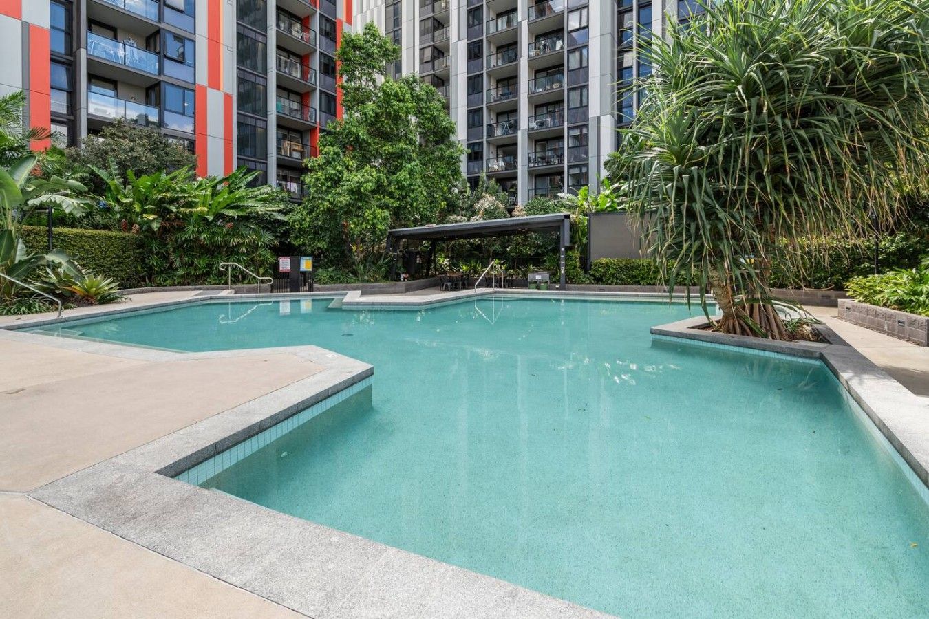 Una piscina circondata da un giardino e un edificio moderno sullo sfondo.