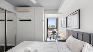 Una camera d'albergo con un letto, una scrivania con una sedia, una finestra vista e un armadio.