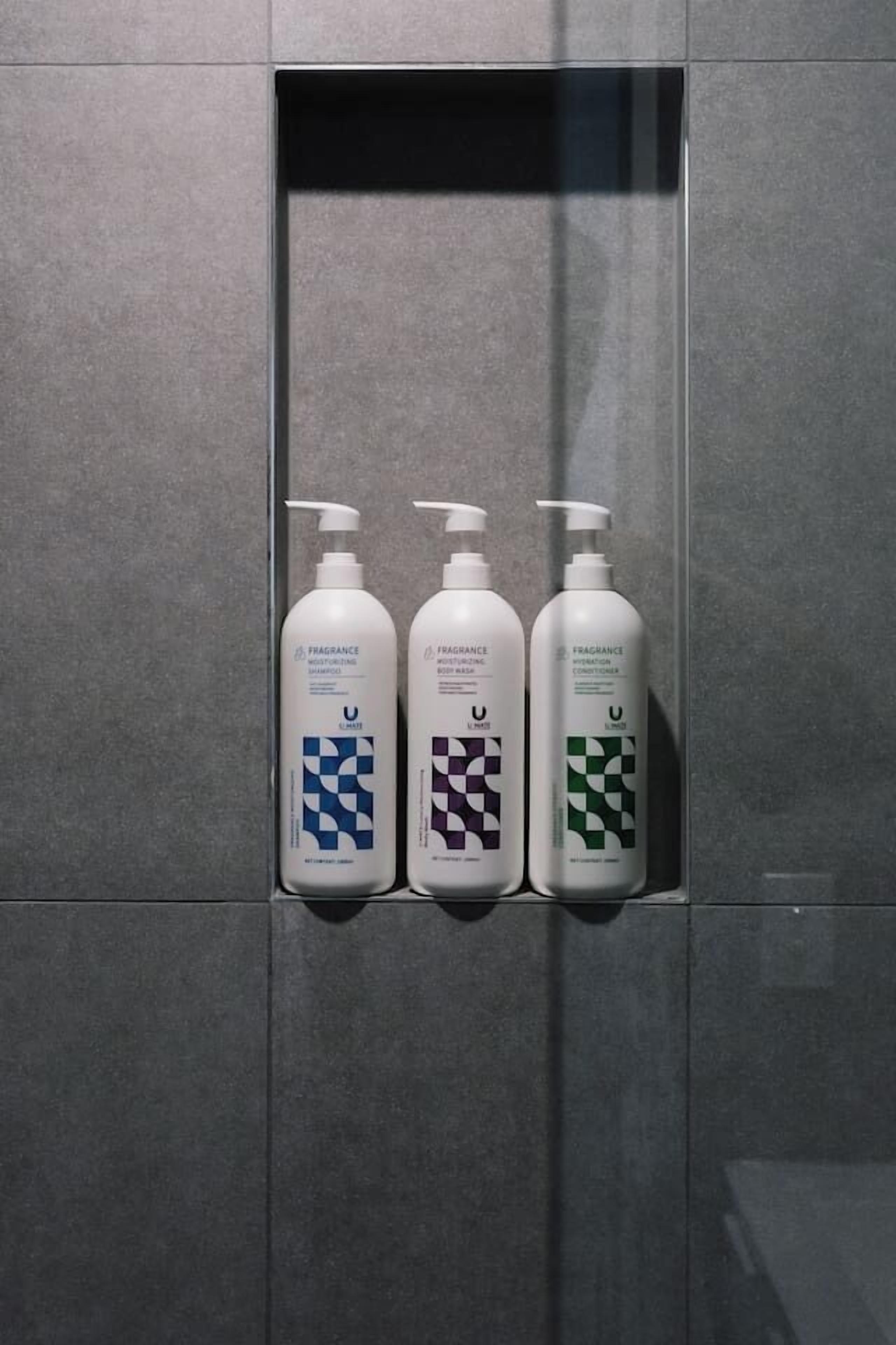 Three bottles of fragrance products in a tiled wall compartment.