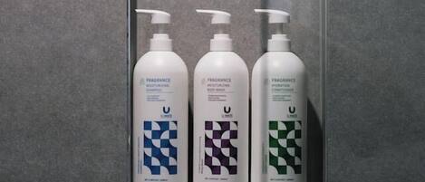 Three bottles of fragrance products in a tiled wall compartment.