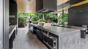 Una cucina moderna con isola in acciaio inox, cappa aspirante e vista sul verde circostante.