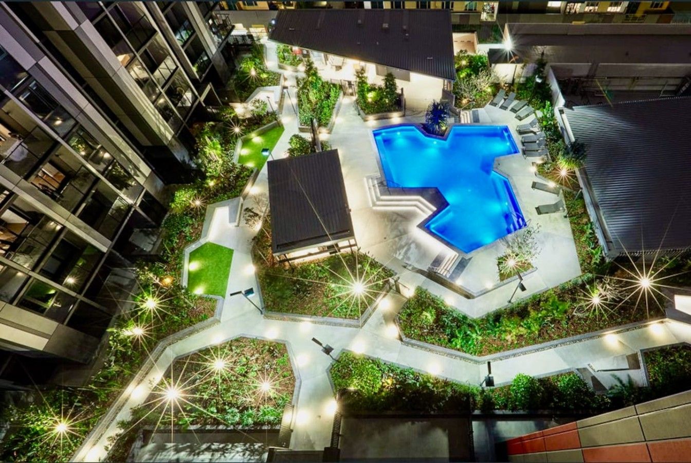 Area piscina sul tetto con design geometrico, circondata da vegetazione e vialetti.