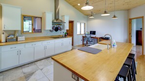 A modern kitchen with wooden cabinets, a large island, pendant lights, and a visible stove hood. - Fish, Hike & More! Home w/ Views in Stevensville (Stevensville)