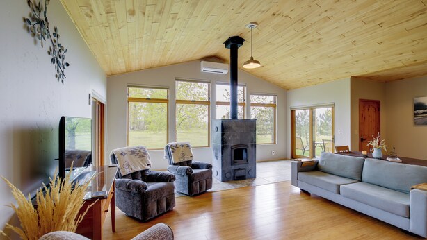 A spacious living room with a wooden ceiling, a fireplace, a sofa, and two armchairs. - Fish, Hike & More! Home w/ Views in Stevensville (Stevensville)