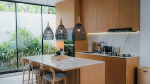 A modern kitchen with a central island, wooden cabinets, and pendant lighting. - 3-bedroom Aquamarine villa in awesome Bali with Private Pool (Bali)