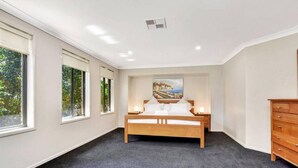 A bedroom with a large bed, a nightstand, a dresser, and a painting on the wall. - Hidden Horizon (Nords Wharf)