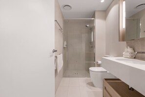 Une salle de bain moderne avec une douche à parois de verre, des toilettes et un lavabo surmonté d’un miroir.