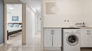 Een moderne hotelkamer met een opgemaakt bed, een wasmachine en een kleine kitchenette.