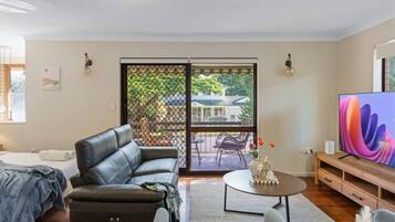 A modern living room with a leather sofa, a coffee table, and a TV on a wooden stand.