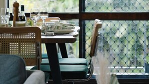 A dining area with a table set for four, chairs, and a view through a large window. - Unbeatable Value | Group/Family | Roomy/Convenient (Robertson)