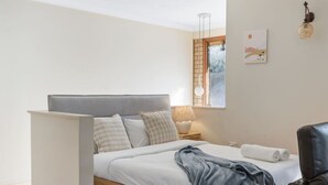 A bedroom with a bed, a nightstand, a lamp, a chair, and a window with a view. - Unbeatable Value | Group/Family | Roomy/Convenient (Robertson)