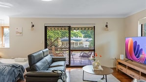 A modern living room with a leather sofa, a coffee table, and a flat-screen TV. - Unbeatable Value | Group/Family | Roomy/Convenient (Robertson)
