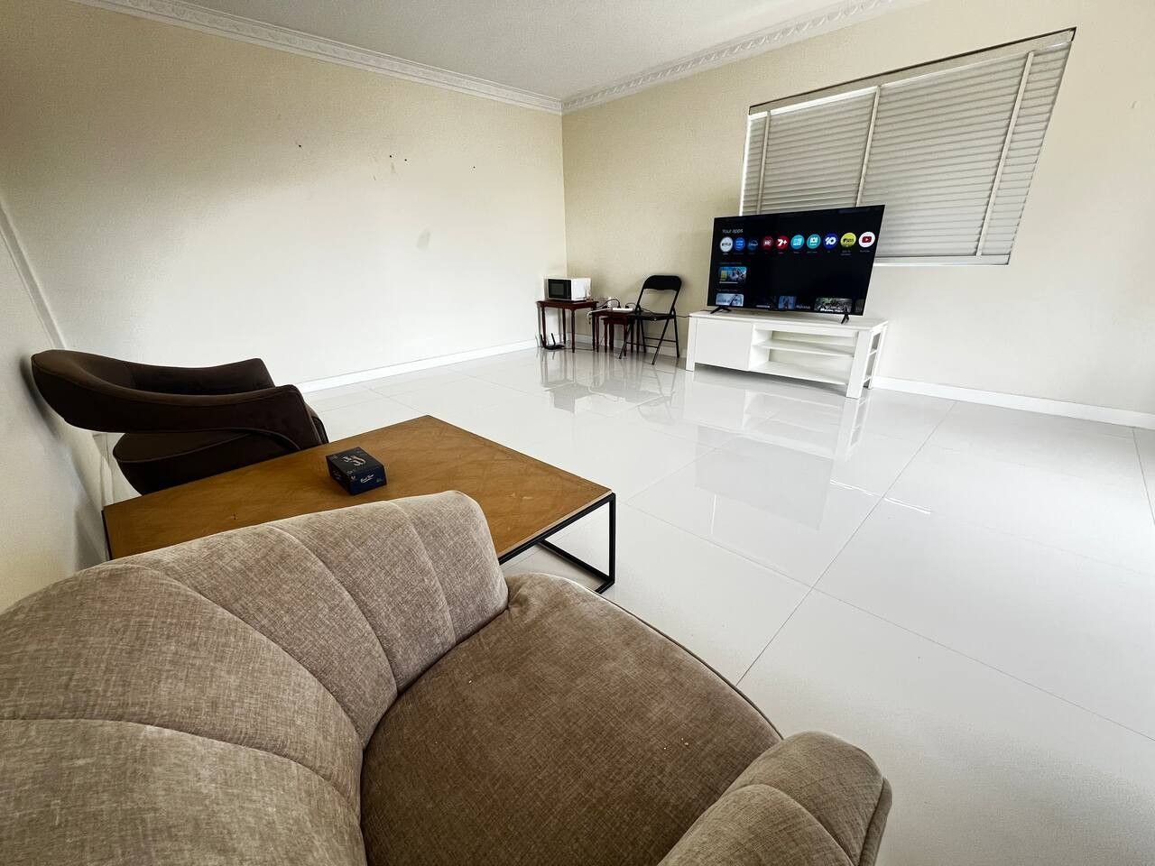 A living room with a sofa, a coffee table, a TV, and a small table with a chair.