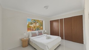 A bedroom with a bed, bedside tables, a window with a view, and a wardrobe.