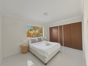Een slaapkamer met een bed, nachtkastjes, een raam met uitzicht en een kledingkast.