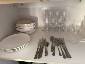 Une table dressée avec de l’argenterie, des assiettes blanches et des verres à vin transparents.