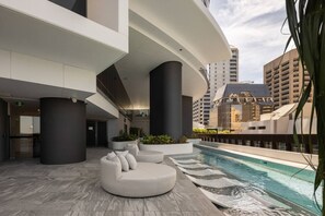 A modern rooftop pool area with a curved seating area and a pool.