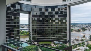 Un bâtiment moderne à la façade incurvée, doté de grandes fenêtres et offrant une vue sur une rivière et le paysage urbain.