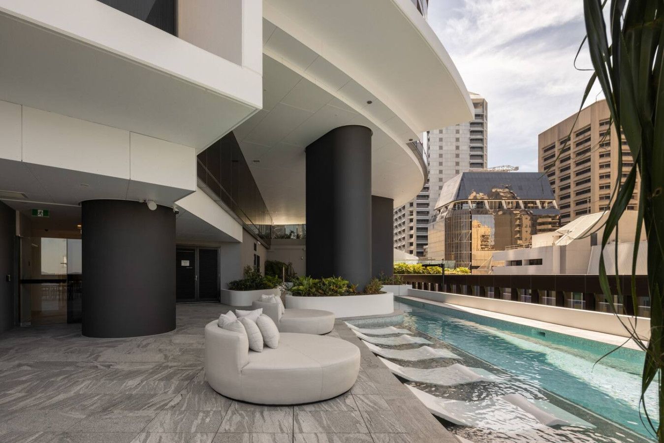 A modern rooftop pool area with a curved seating area and a pool.