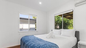 A bedroom with a bed, a window, and a white wall. - 3Beds Value & Comfort Stay | Airport, CBD & Cafes (Bulimba)