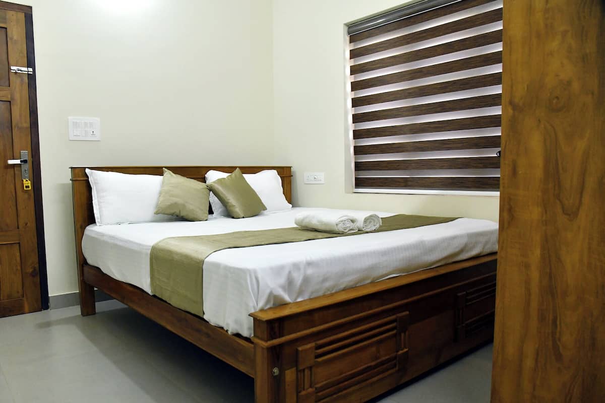 A neatly made bed with white linens, a wooden headboard, and a green throw blanket.