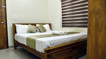 A neatly made bed with white linens, a wooden headboard, and a green throw blanket.