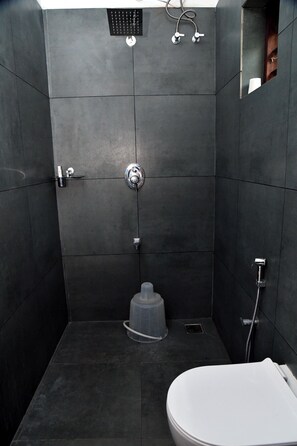 A modern bathroom with a shower, toilet, and a small sink. - Ayush Green - Home Away Home (Thalassery)