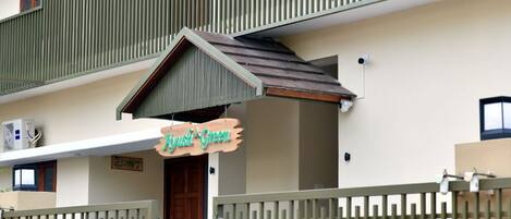 A building with a green facade, a wooden door, and a sign that reads "Just Green".