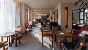 A spacious hotel lobby with wooden furniture, large windows, and indoor plants. - Lijiang Garden vacation PuZhi hotel (Lijiang)